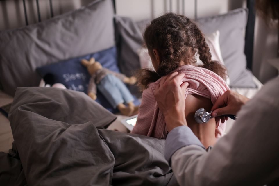 Pediatrician examining a young child during a well-child visit